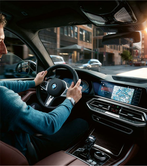 Driver in BMW car using dashboard display with navigation map via Ottocast wireless CarPlay adapter