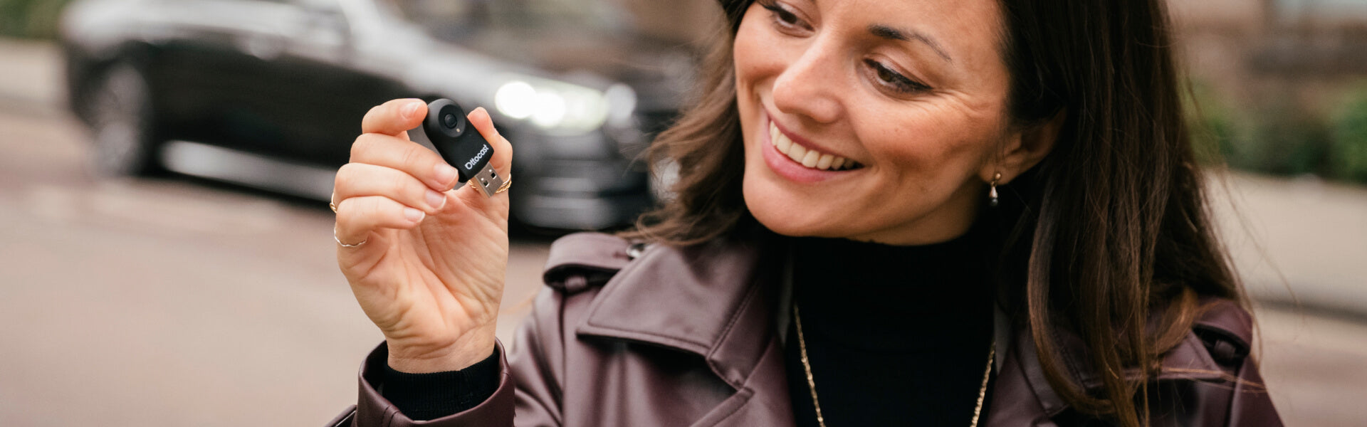 Smiling woman holding Ottocast mini wireless CarPlay and Android Auto adapter for easy in-car connectivity